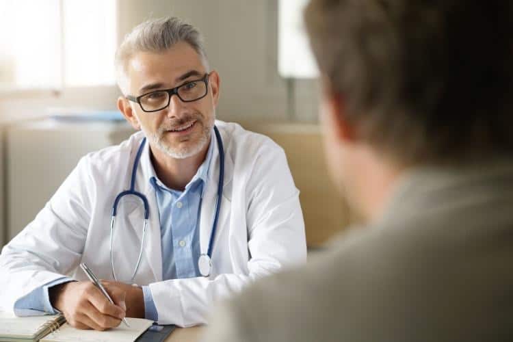 Smiling doctor looks at patient who wants to quit drinking