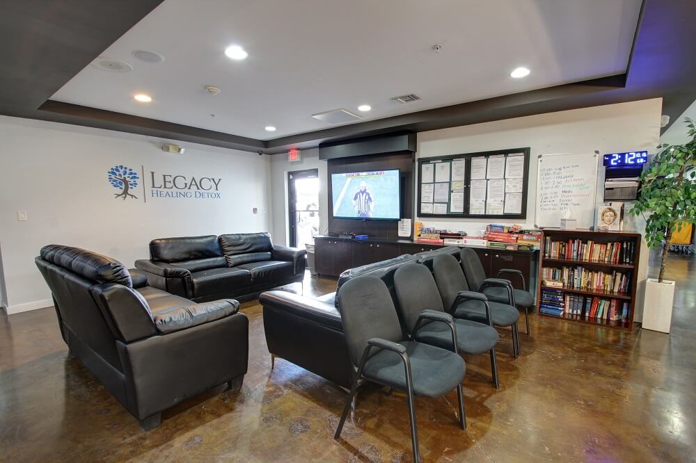 A waiting room with sofas, chairs, and bookshelves at Legacy Healing Center.