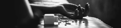 An unconscious person lies on a bed next to an open bottle of fentanyl pills