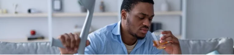 Distressed man looks at an alcoholic drink in his hand