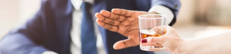 Outstretched hand of man in business suit refuses glass of whiskey