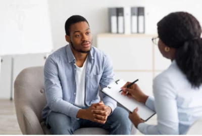 Concerned-looking man talks to a REBT-trained mental health professional about his mental health condition