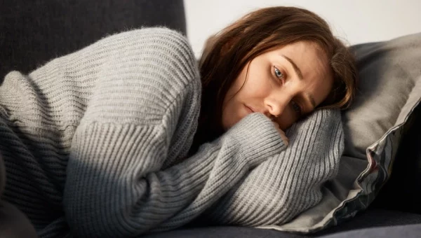 Woman going through tramadol withdrawal lays on couch with pained expression