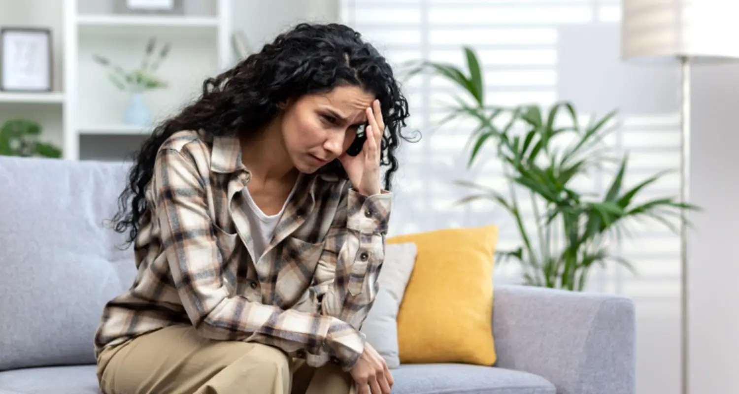 Sad, thin woman who’s addicted to drugs looks sad and worried on the couch