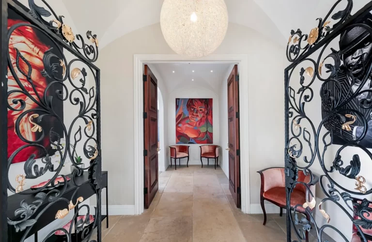 Hallway with decorative cast-iron gages, artwork with red and black motifs, and red velvet chairs