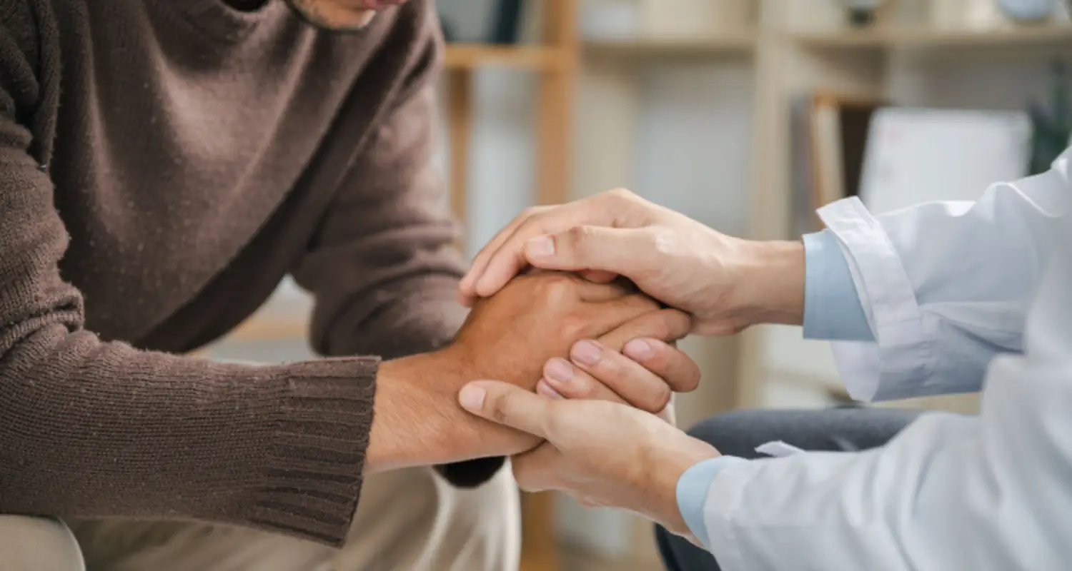 medical professional holds hands of a meth addict in detox