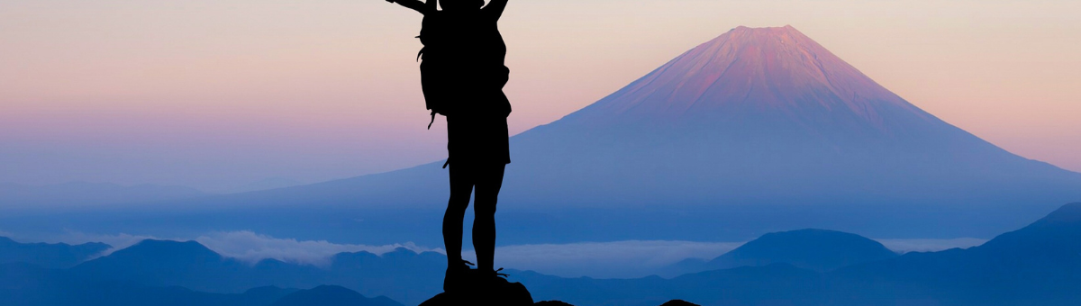 Hiker celebrating on a hill with the sunset in the background