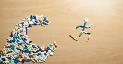 The image creatively depicts a figure made of pills running away from a larger pill-shaped Pac-Man, symbolizing the struggle to escape prescription drug addiction.